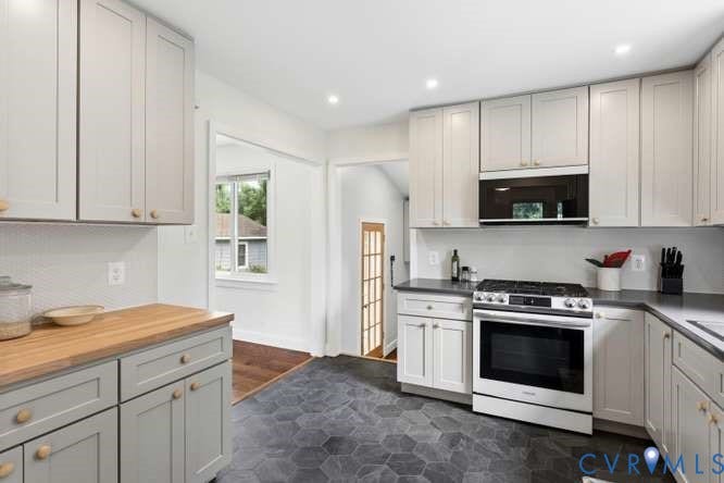 Kitchen featuring light gray cabinetry with brass hardware, dark hexagonal tile flooring, and a built-in microwave