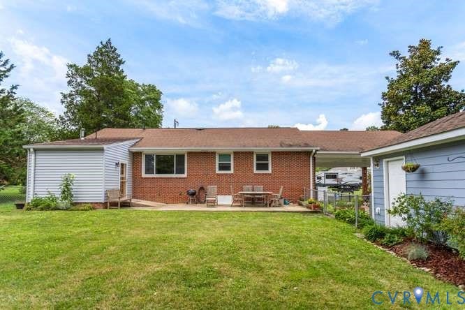 Spacious backyard featuring a manicured lawn, brick exterior, and an attached extension with siding