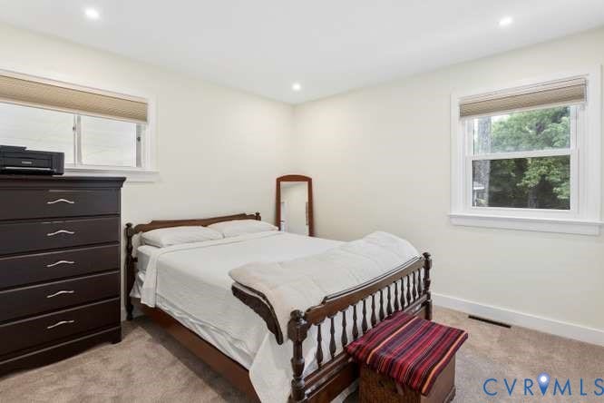 Neutral-toned room with plush carpet flooring, two windows featuring blinds, and recessed lighting