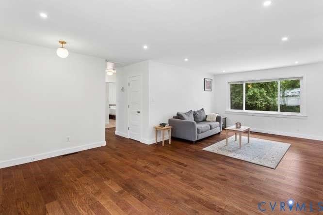 Spacious room featuring rich wood-finish flooring, recessed lighting, and a large multi-pane window