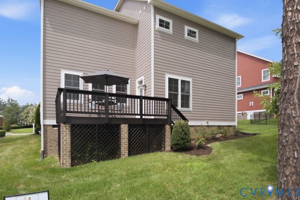 6991 Carden Park Drive, Carden Park, Moseley, VA 23120 Rear exterior featuring a brown composite deck with black railings and lattice skirting, accessed via a door from the home
