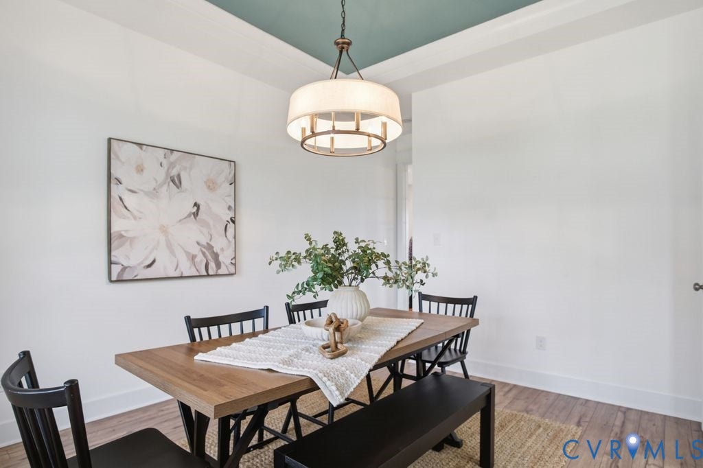 6991 Carden Park Drive, Carden Park, Moseley, VA 23120 Dining space featuring a coffered ceiling with a contrasting painted inset, a modern drum pendant light, and wood-finish flooring