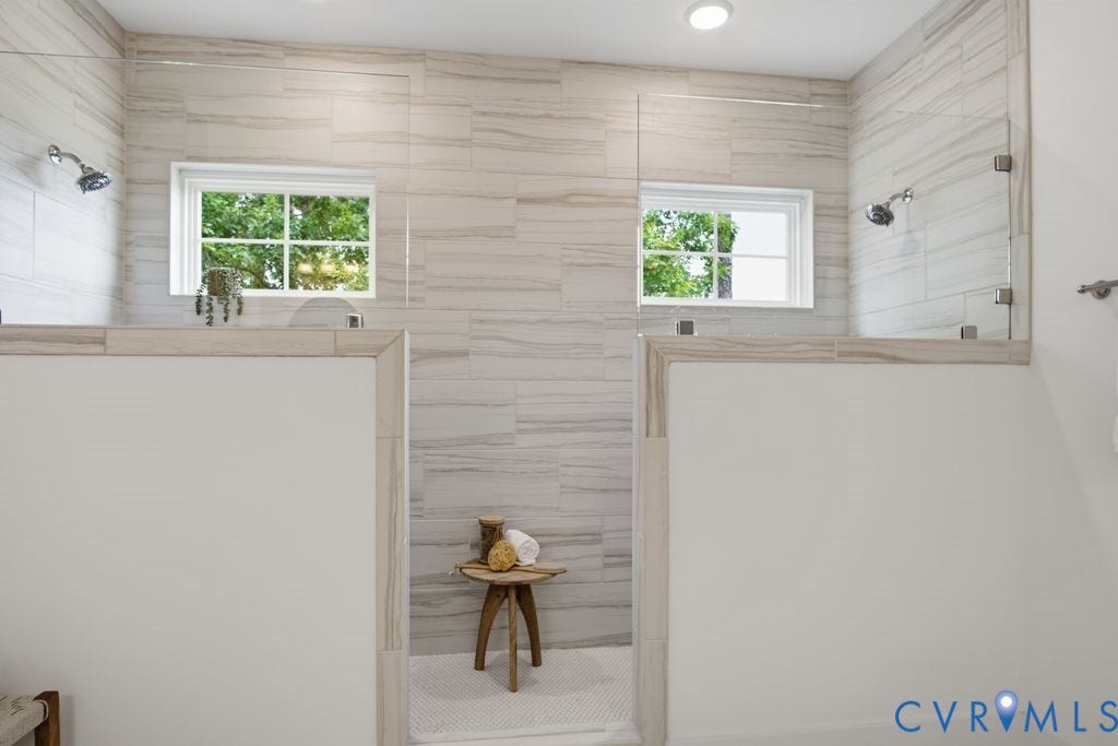 6991 Carden Park Drive, Carden Park, Moseley, VA 23120 Dual shower enclosures featuring light-toned horizontally-laid tile walls, individual chrome showerheads, and clear glass panels