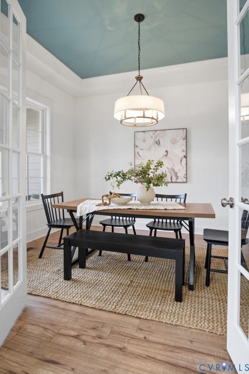 6991 Carden Park Drive, Carden Park, Moseley, VA 23120 French doors opening to a dining space featuring a tray ceiling with a contrasting paint finish, wood-finish flooring, and a drum-style chandelier