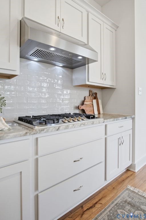 6991 Carden Park Drive, Carden Park, Moseley, VA 23120 Kitchen featuring a stainless steel range hood, white subway tile backsplash, gas cooktop, light-toned countertops, and light-colored cabinetry with modern hardware