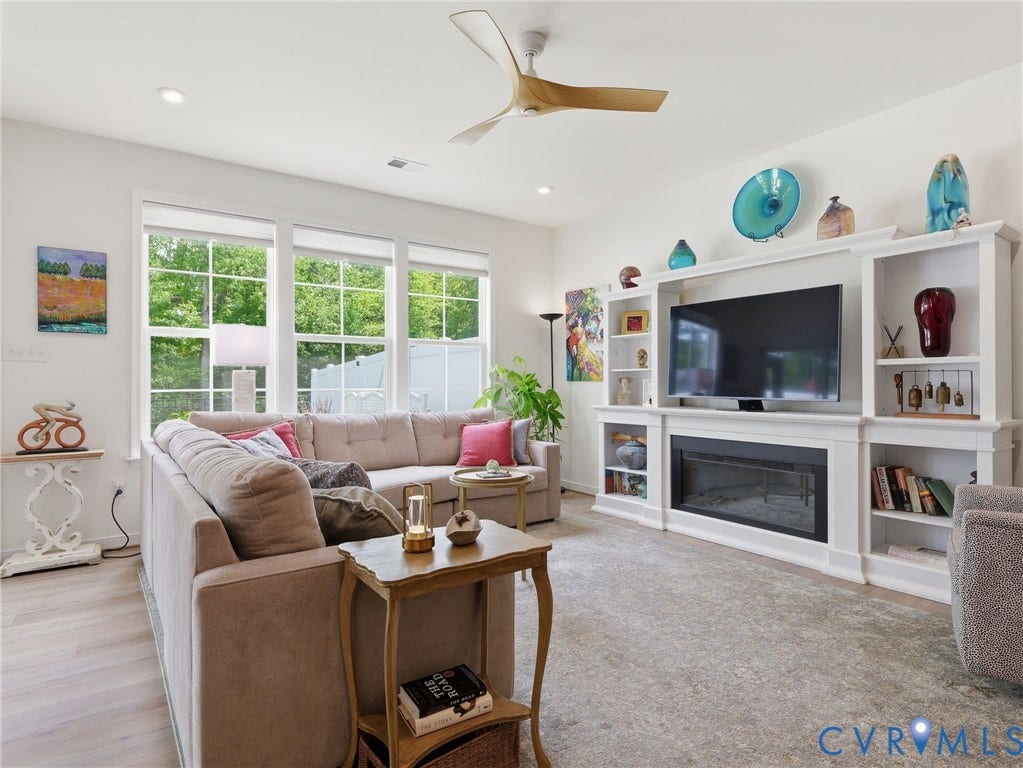 9237 Cerulean Place, Richmond, VA 23238 Beautiful great room with expansive windows providing abundant natural light, updated ceiling fan, and stylish wall cabinet with electric fireplace.
