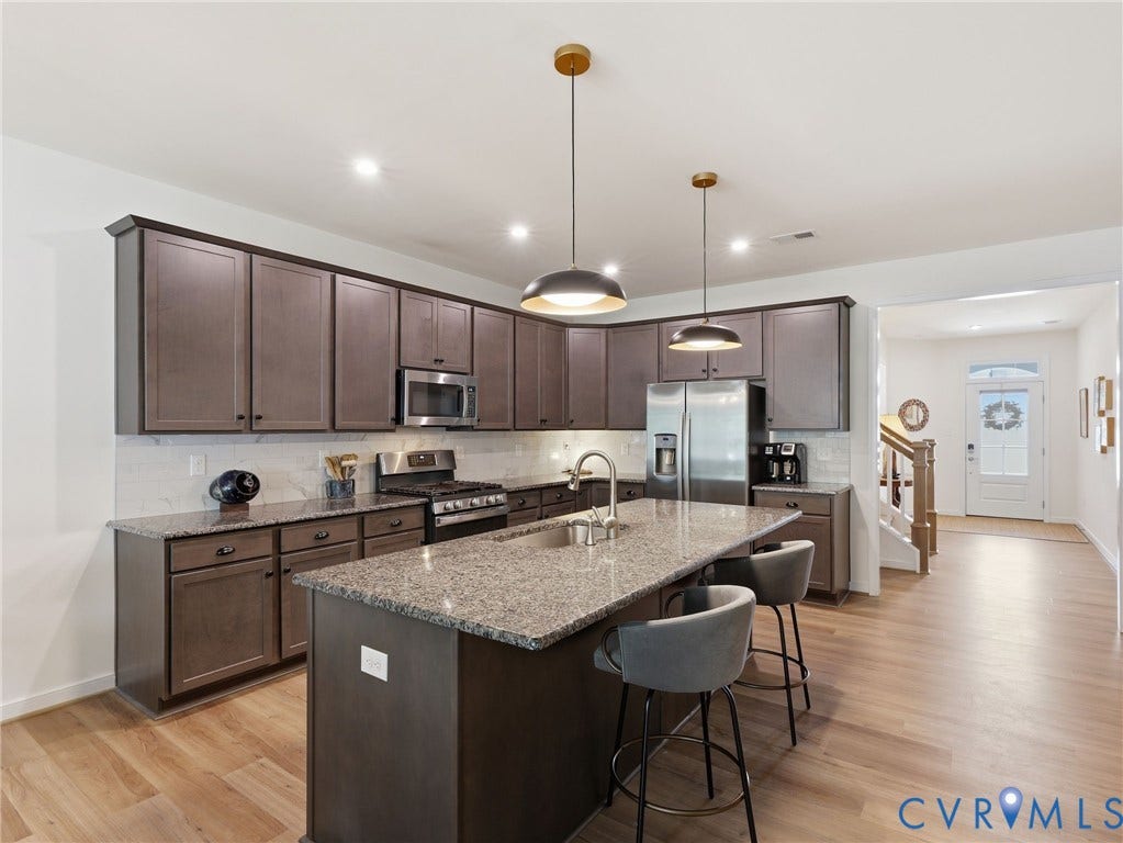 9237 Cerulean Place, Richmond, VA 23238 Designed for gathering, cooking, and living this kitchen blends luxury finishes with everyday functionality. Wood laminate flooring.