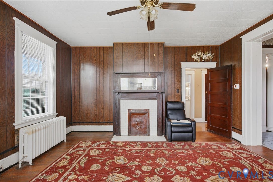3110 North Avenue, Brookland Park, Richmond, VA 23222 Wood-finish wall paneling, fireplace with a decorative mantel, wood-finish flooring, white window trim, and a ceiling fan with integrated lighting