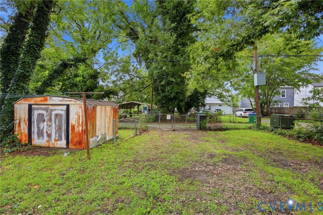 3110 North Avenue, Brookland Park, Richmond, VA 23222 Spacious grounds featuring mature shade trees, level lawn, and a detached storage structure with weathered wood siding and white-trimmed doors