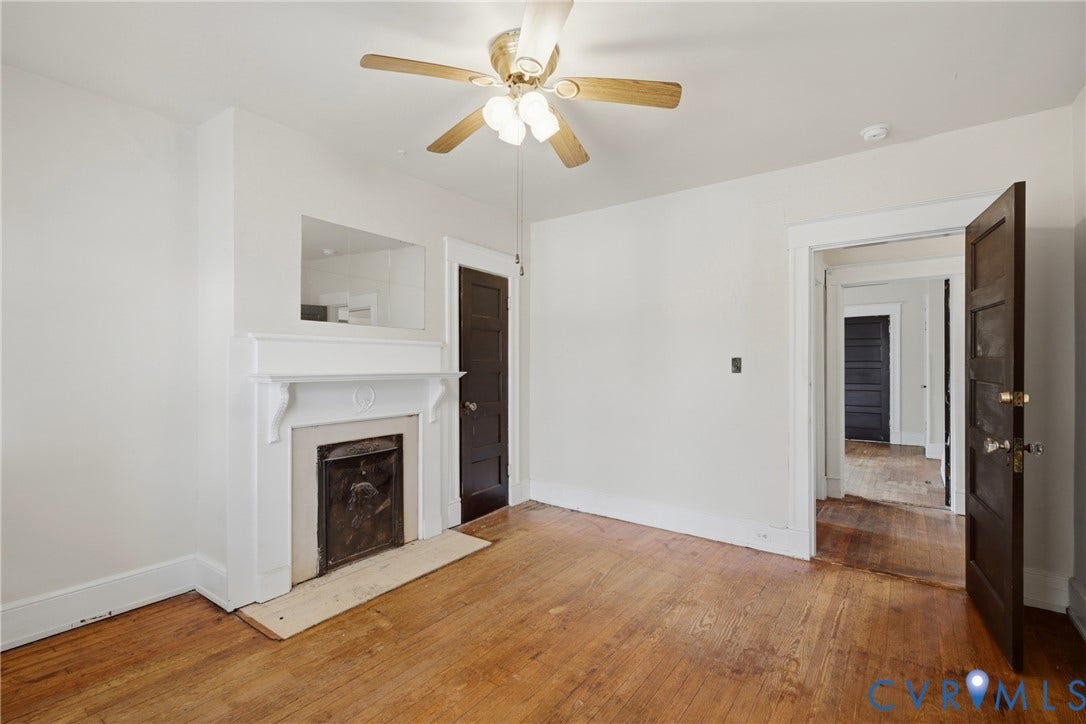 3110 North Avenue, Brookland Park, Richmond, VA 23222 Hardwood flooring, white painted walls, decorative fireplace, ceiling fan with light fixture, and dark wood-paneled door