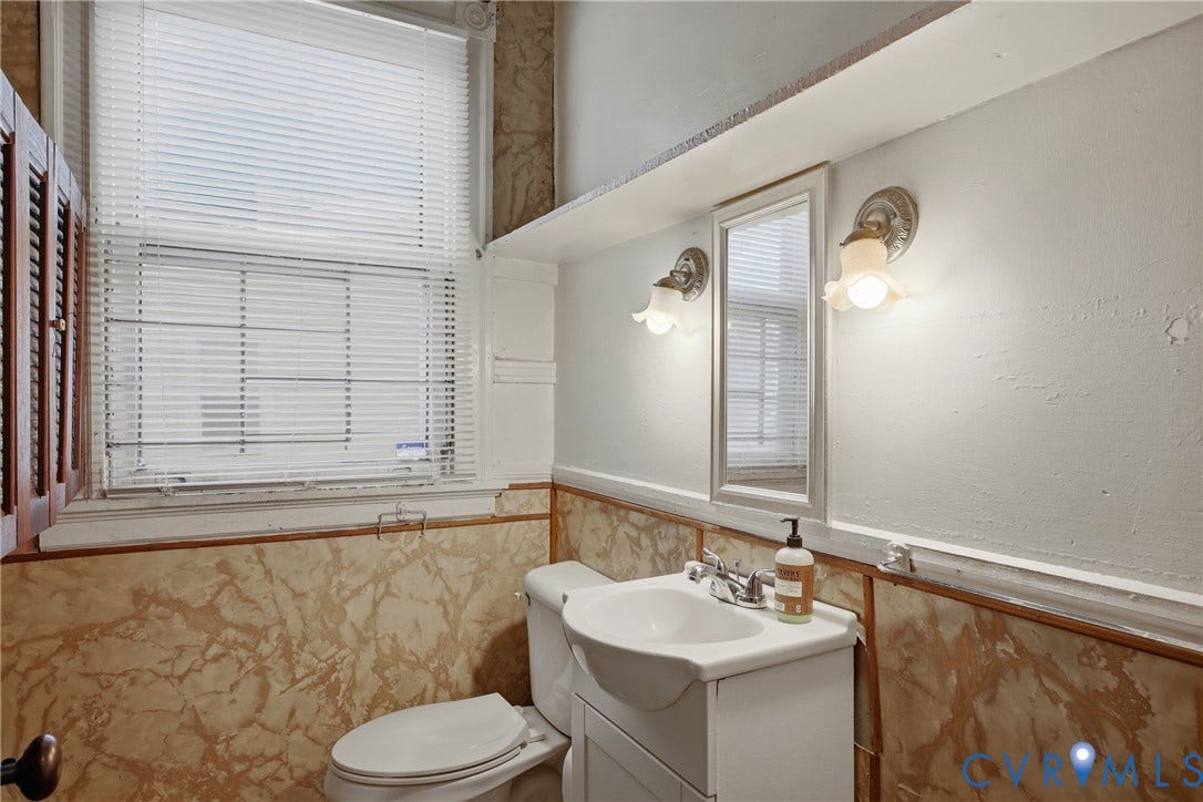 3110 North Avenue, Brookland Park, Richmond, VA 23222 Built-in wooden cabinetry, window with blinds, wall-mounted light fixtures, vanity with integrated sink, and patterned wall wainscoting
