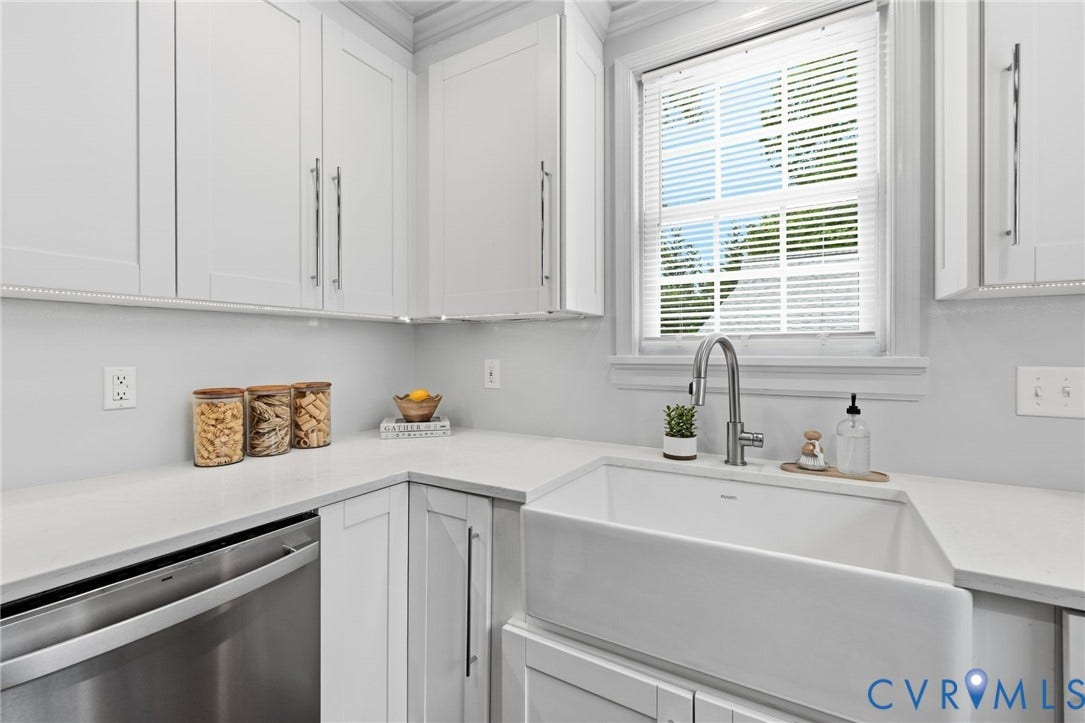 1002 Normandy Drive, Henrico, VA 23229 White shaker-style cabinetry with chrome hardware, white solid surface countertops, a farmhouse-style sink with a gooseneck faucet, and a stainless steel dishwasher