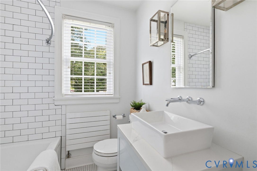 1002 Normandy Drive, Henrico, VA 23229 White subway tile surround, vessel sink, wall-mounted faucet, rectangular vanity mirror, and white window blinds