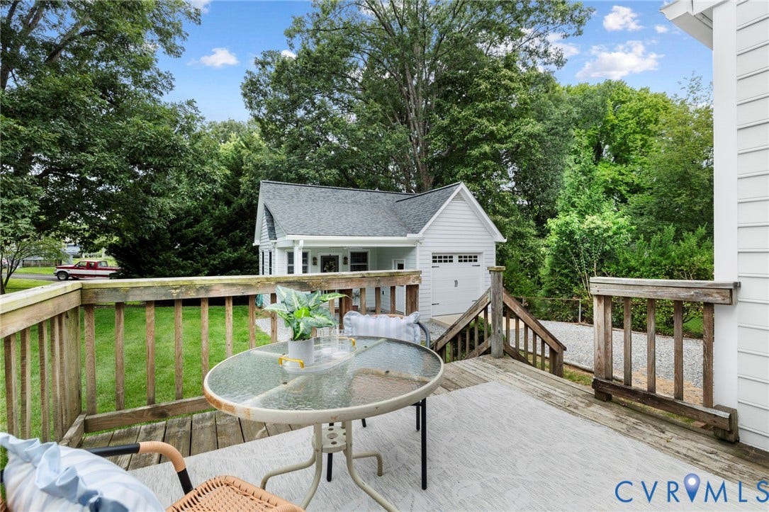 1002 Normandy Drive, Henrico, VA 23229 Spacious outdoor deck with wood railings, a detached garage featuring a white door, and a gravel driveway