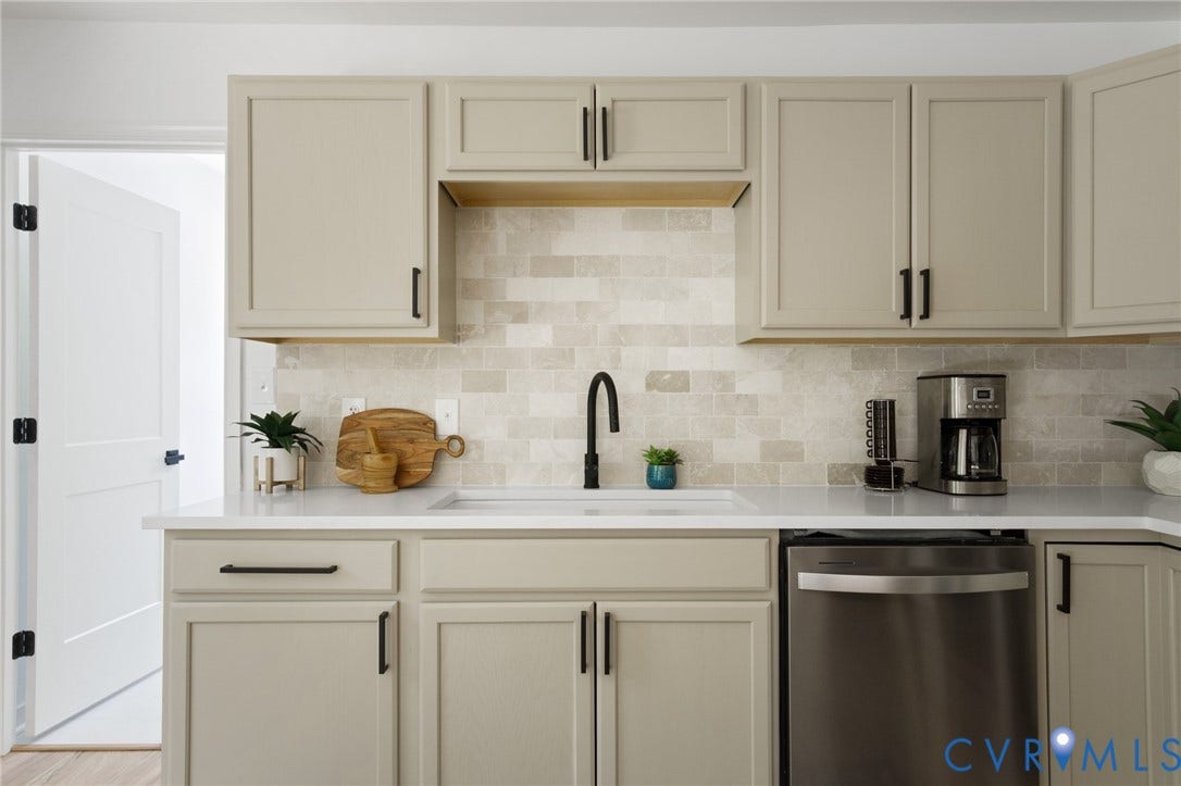 3056 Davis Mill Road, Goochland, VA 23063 Modern kitchen featuring neutral-toned cabinetry with black hardware, a white undermount sink, a matte black gooseneck faucet, a light-toned subway tile backsplash, and light-toned countertops
