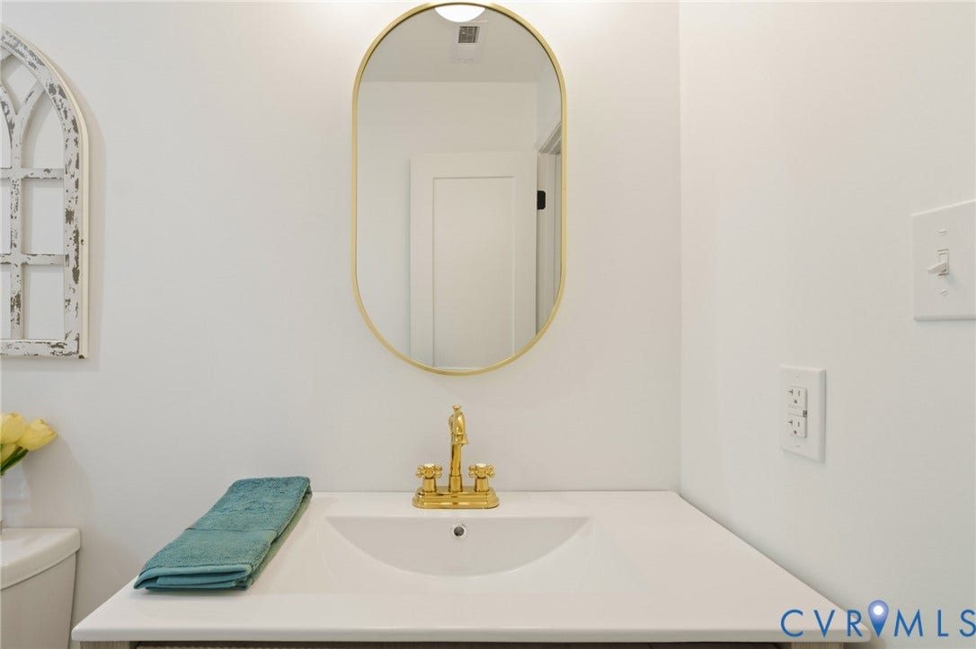 3056 Davis Mill Road, Goochland, VA 23063 Vanity with integrated sink, gold-finish faucet, and coordinating oval mirror