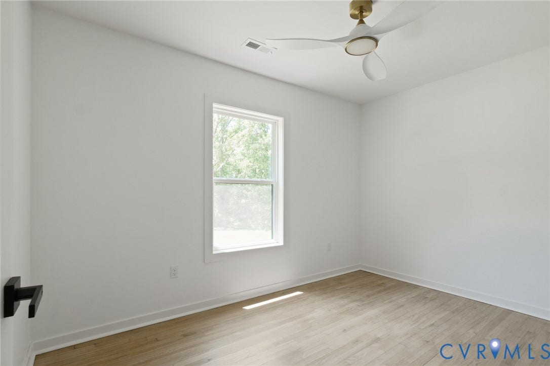 3056 Davis Mill Road, Goochland, VA 23063 Bright interior room featuring a large window, wood-finish flooring, white walls, and a contemporary ceiling fan with a brass-tone fixture