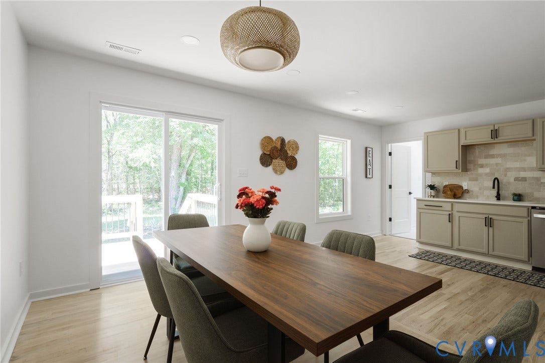 3056 Davis Mill Road, Goochland, VA 23063 Open-concept dining area with wood-finish flooring, a contemporary woven light fixture, and a large sliding glass door opening to an outdoor deck