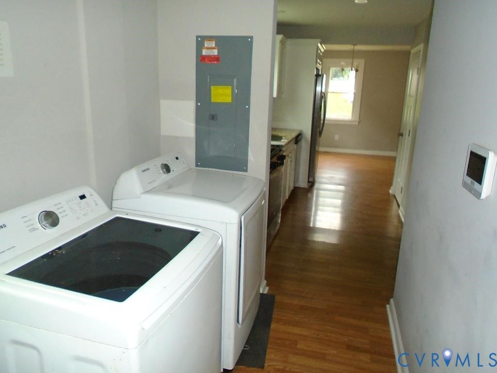 3406 Mike Road, Richmond, VA 23234 Laundry area featuring a utility panel and wood-finish flooring extending into an adjacent kitchen with white cabinetry and stainless steel appliances
