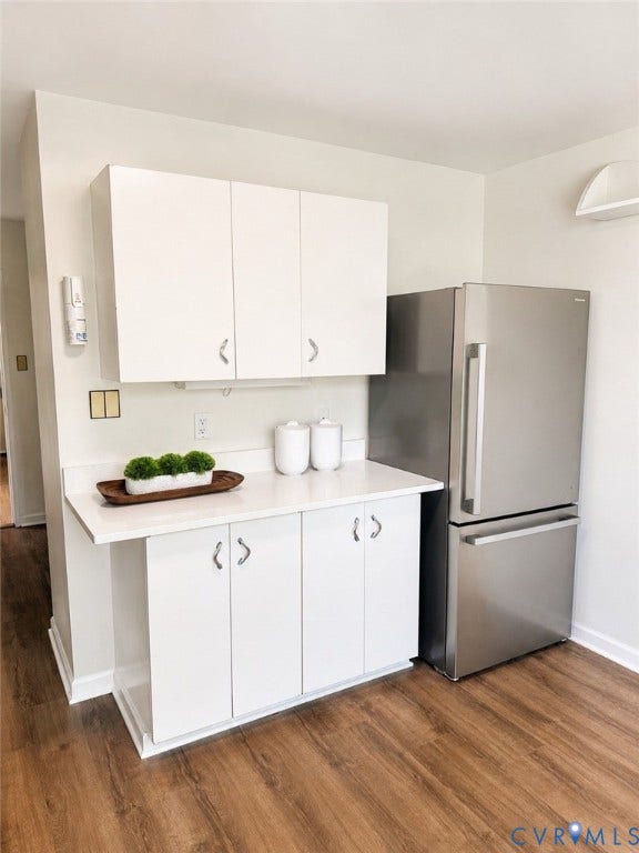5100 Monument Avenue, #503, Willow Lawn, Richmond, VA 23230 Compact kitchen area featuring white cabinetry with brushed nickel hardware, a light-toned countertop, wood-finish flooring, and a stainless steel refrigerator