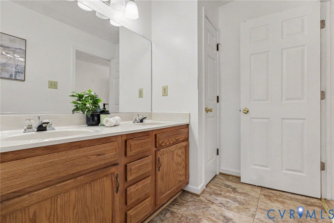 931 Hunters Run Drive, Henrico, VA 23223 Double vanity with wood-finish cabinetry, integrated sinks, white countertop, and expansive wall-mounted mirror