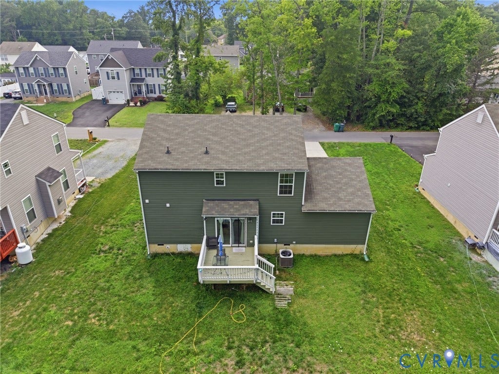 10155 Virginia Road, Glen Allen, VA 23060 Rear exterior featuring dark green siding, a light gray roof, and a ground-level deck with white railings