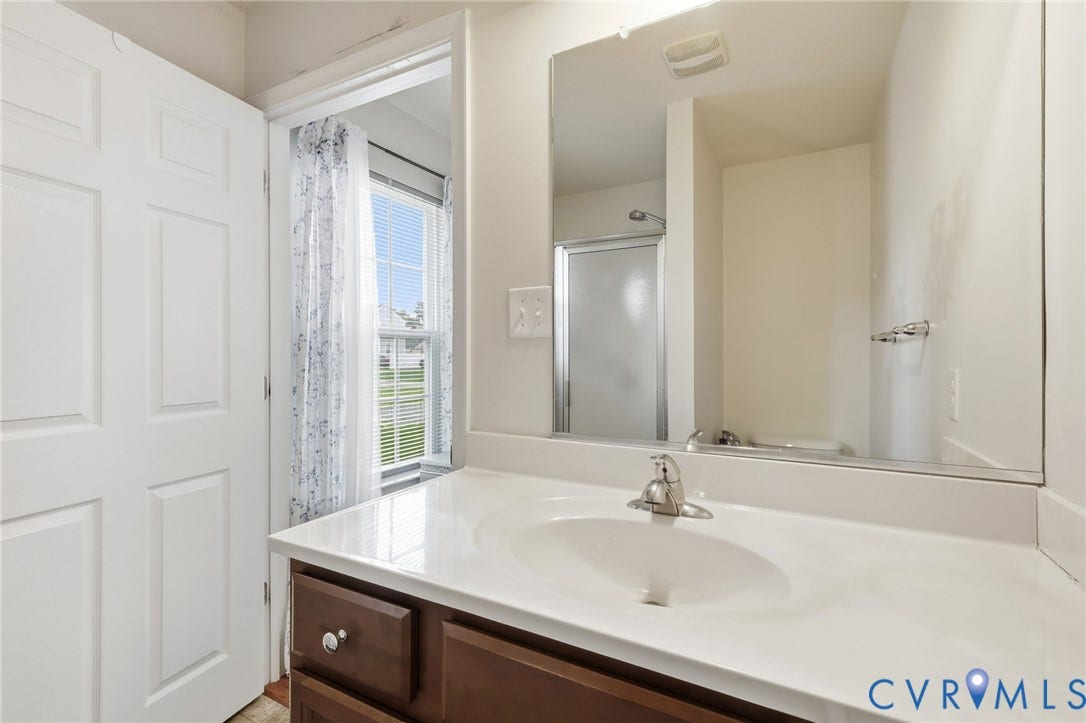 10155 Virginia Road, Glen Allen, VA 23060 White vanity with integrated sink, brushed nickel faucet, and a large wall-mounted mirror