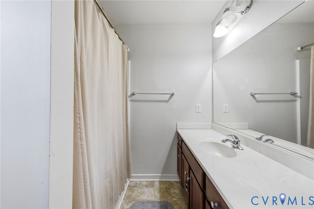 10155 Virginia Road, Glen Allen, VA 23060 Bathroom featuring a spacious vanity with a white countertop, an integrated sink with a chrome faucet, and dark wood-finish cabinetry