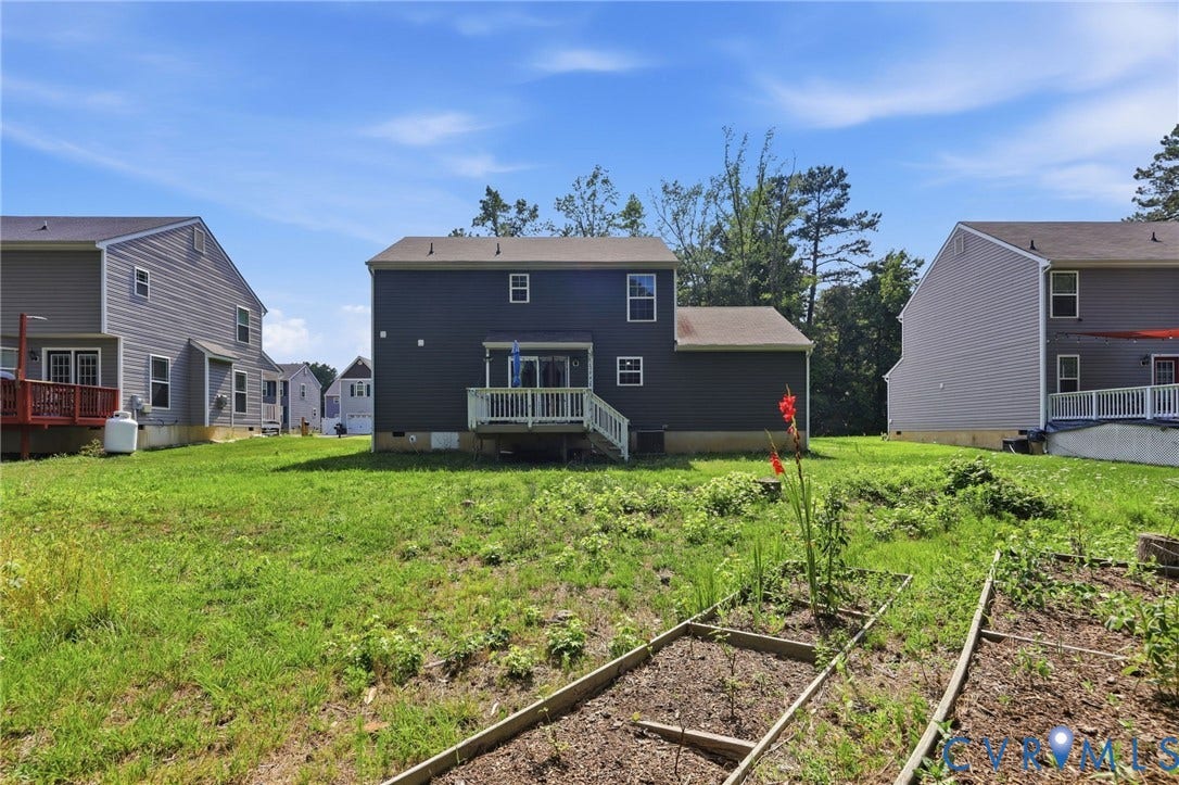 10155 Virginia Road, Glen Allen, VA 23060 Expansive rear lawn featuring a two-story residence with dark siding, a ground-level deck, and multiple windows