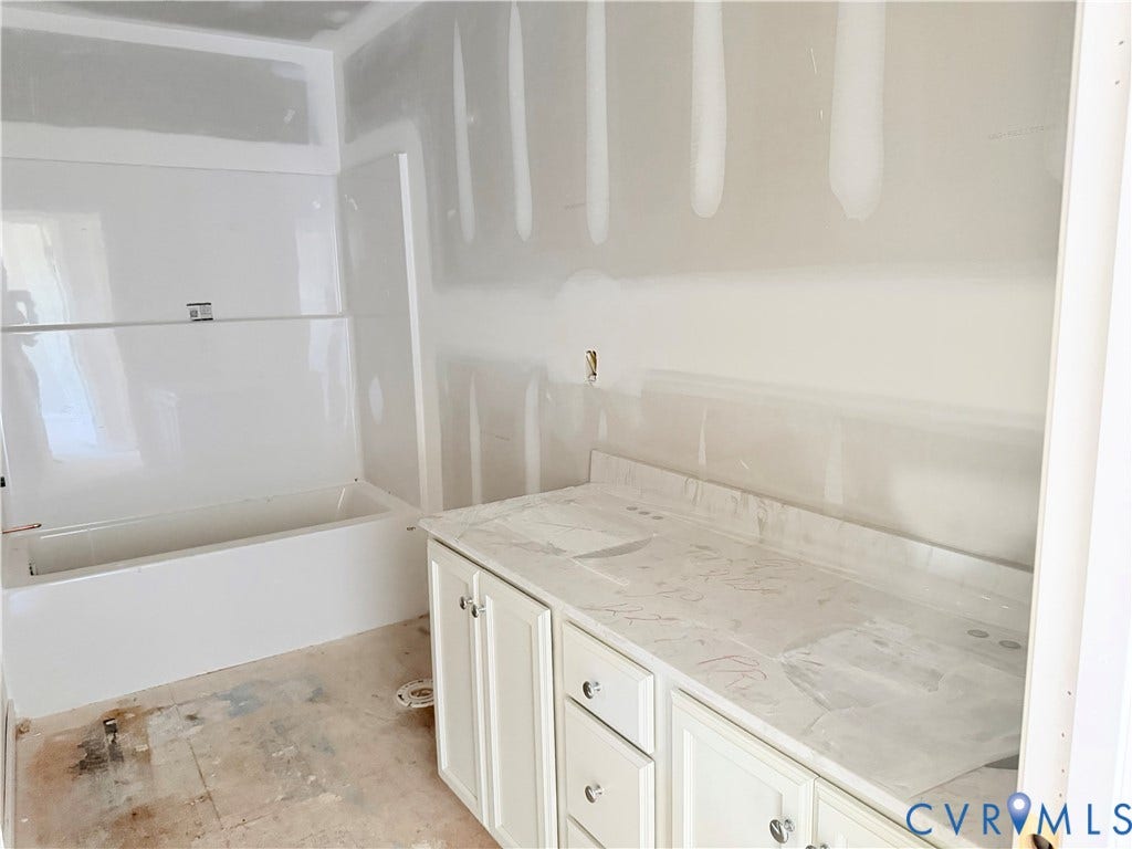 11130 Somerset Bluff Court, Somerset Hills, Glen Allen, VA 23059 White vanity cabinetry with crystal knobs, a light-toned countertop, and an integrated white bathtub with surround