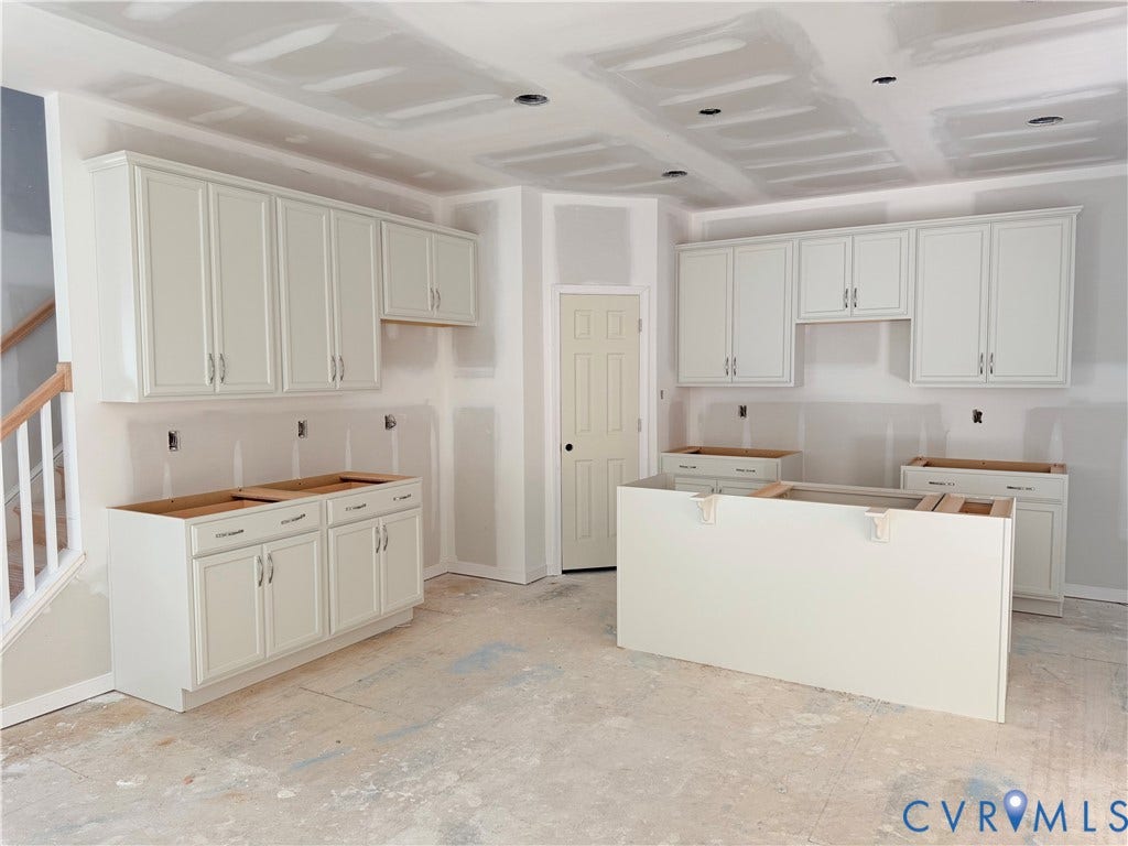 11130 Somerset Bluff Court, Somerset Hills, Glen Allen, VA 23059 White shaker-style cabinetry with chrome hardware, an unfinished island, and a partially enclosed staircase with natural wood railings