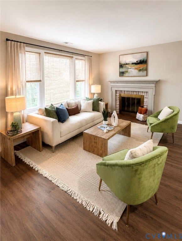 3909 Corbin Street, Wahington Park, Richmond, VA 23222 Living area featuring wood-finish flooring, a fireplace with a white mantel and brick surround, and a triple window with blinds and drapes