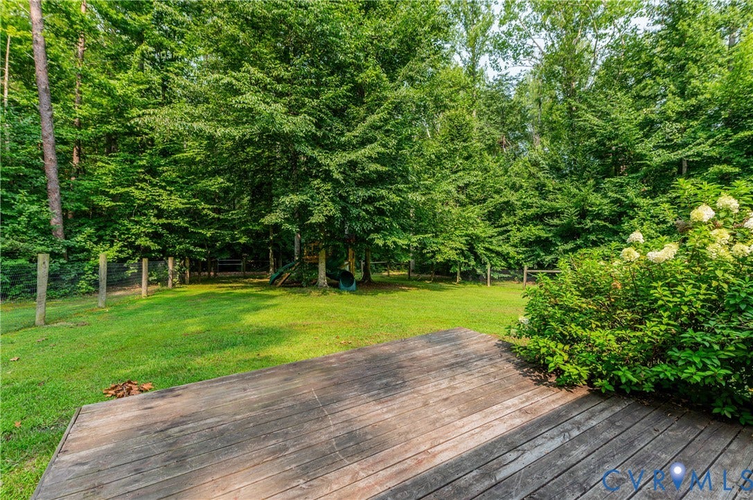 384 Tillar Lane, Mineral, VA 23117 Expansive outdoor living area featuring a wooden deck, established landscaping, and a fenced perimeter