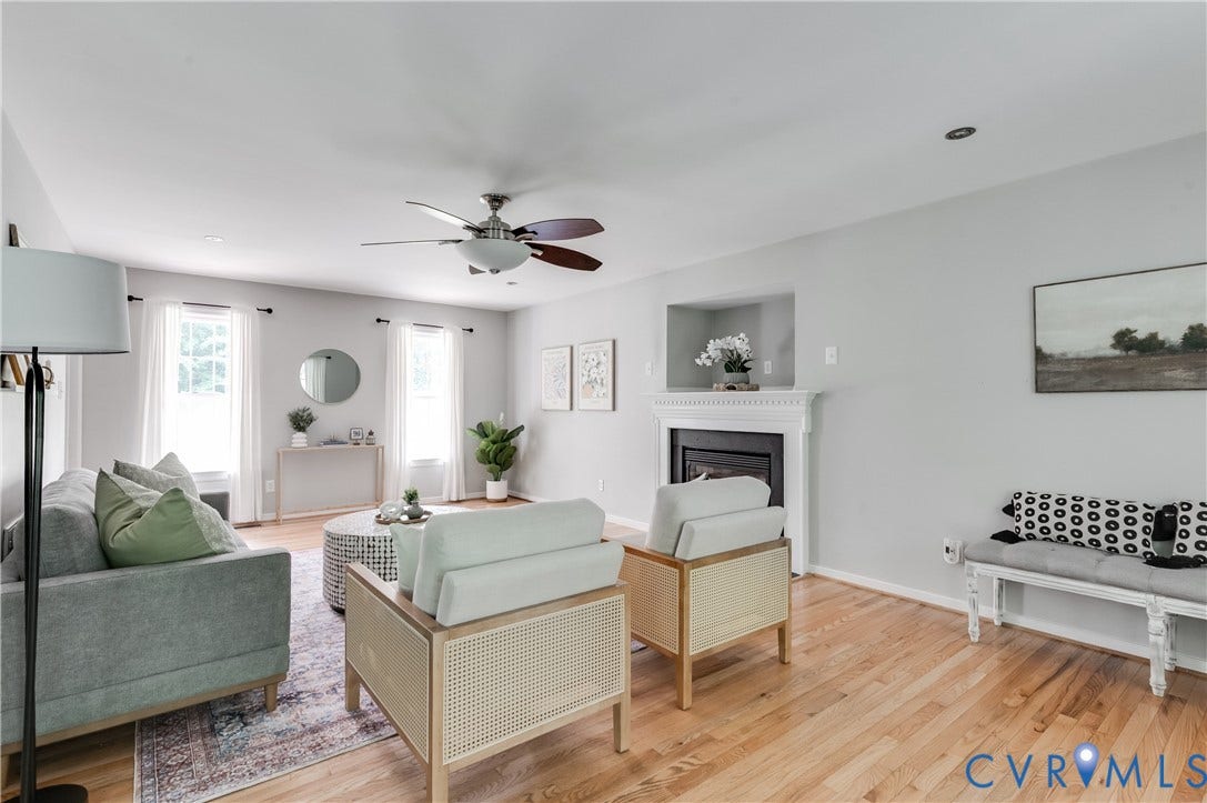 384 Tillar Lane, Mineral, VA 23117 Spacious living area featuring wood-finish flooring, a ceiling fan with integrated lighting, and a fireplace with a white mantel and recessed niche
