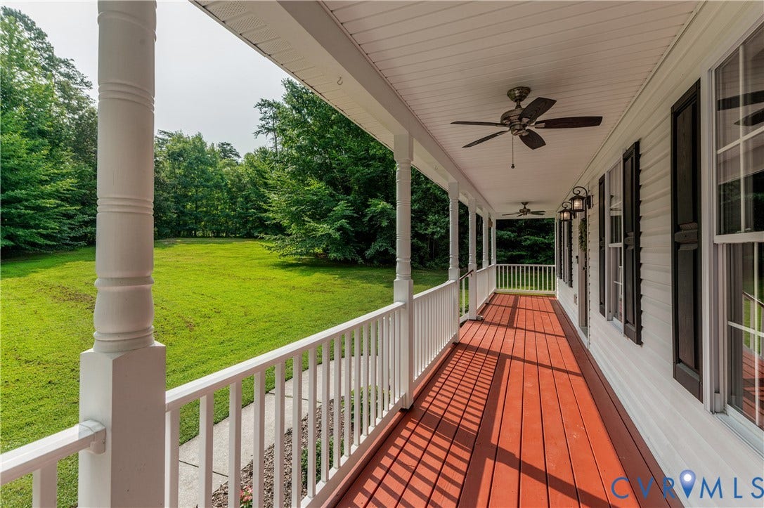 384 Tillar Lane, Mineral, VA 23117 Expansive front porch featuring rich red wood-finish flooring, multiple ceiling fans, white columns, and white balusters