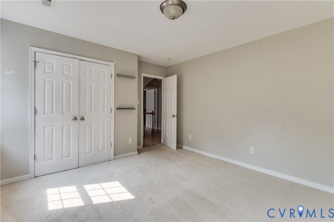 384 Tillar Lane, Mineral, VA 23117 Neutral-toned carpeted room featuring a double-door closet with paneling and brushed nickel hardware, light gray wall paint, and white trim molding