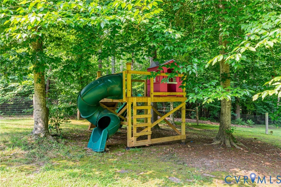 384 Tillar Lane, Mineral, VA 23117 Outdoor playset featuring a red clubhouse, green spiral slide, and wooden ladder
