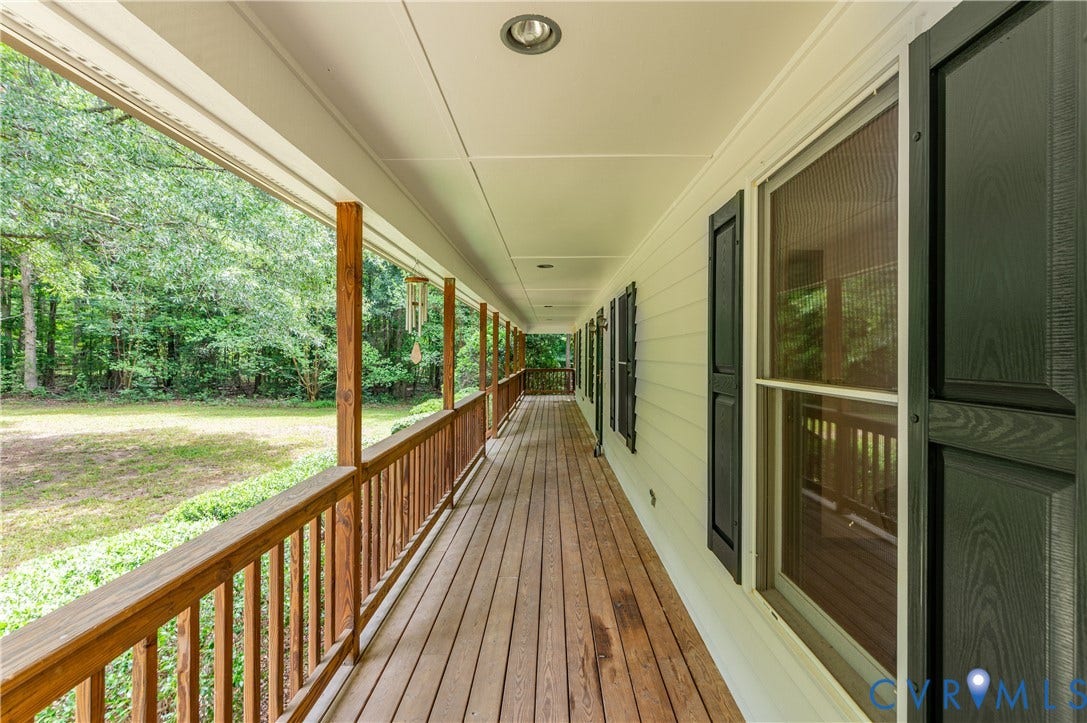 4415 Spoonbill Drive, Powhatan, VA 23139 Expansive covered porch featuring wood-finish decking and railing, recessed lighting, and multiple windows with dark shutters