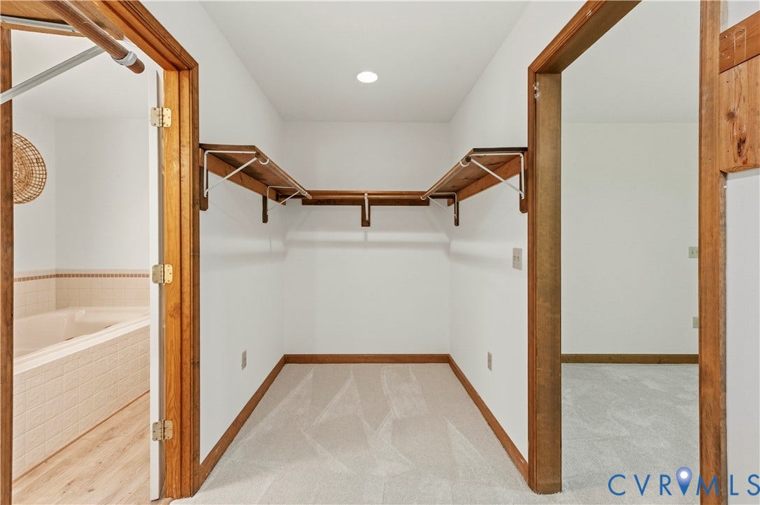4415 Spoonbill Drive, Powhatan, VA 23139 Walk-in closet featuring light carpeting, wood trim, and built-in wood shelving with hanging rods
