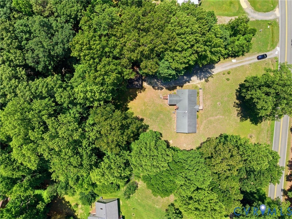 10111 Tunstall Road, New Kent, VA 23124 Expansive wooded property featuring a single-story residence with a gray roof, surrounded by mature trees and natural landscaping, with a gravel driveway and paved road frontage