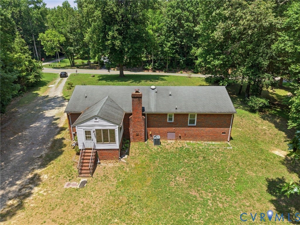 10111 Tunstall Road, New Kent, VA 23124 Brick residence featuring a sunroom addition with white siding, an asphalt shingle roof, and a red brick chimney