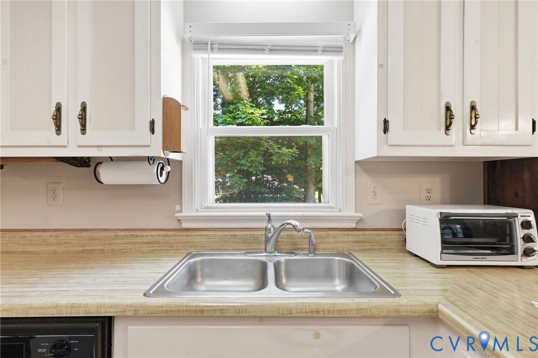10111 Tunstall Road, New Kent, VA 23124 Kitchen sink area featuring a double basin stainless steel sink with a chrome faucet, set into a light wood-finish countertop
