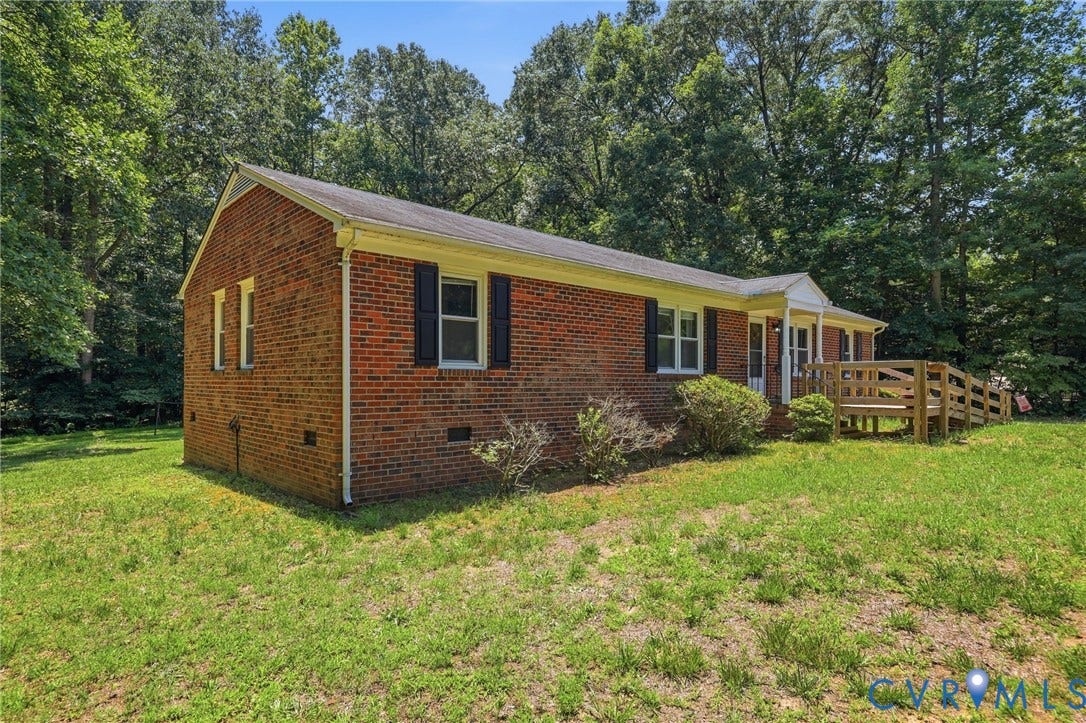 10111 Tunstall Road, New Kent, VA 23124 Brick-clad single-story residence featuring a front porch with a wood ramp, dark window shutters, and a sloped roof