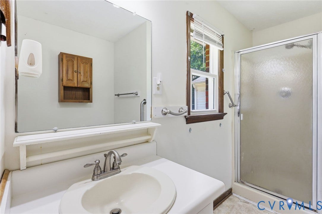 10111 Tunstall Road, New Kent, VA 23124 Bathroom featuring a glass-enclosed shower, single-pane window with wood trim, wall-mounted medicine cabinet, vanity with an integrated sink, and an expansive wall mirror