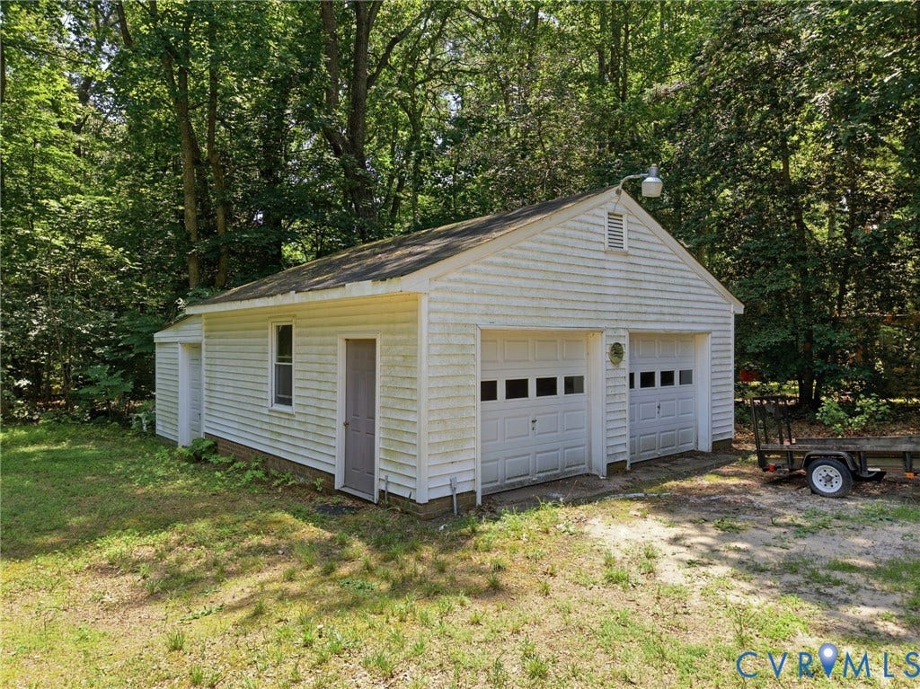 10111 Tunstall Road, New Kent, VA 23124 Detached two-car garage featuring white horizontal siding, two overhead doors with window accents, a side entry door, and a single window