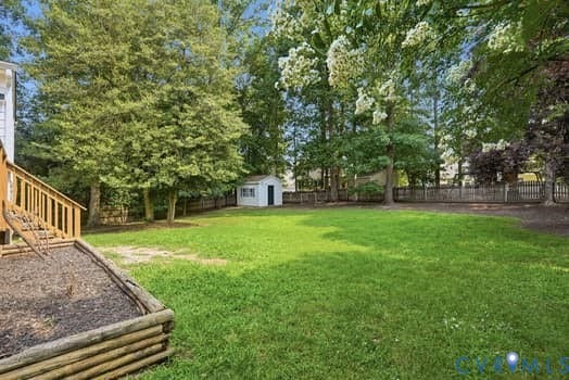 5213 Wheat Ridge Place, Chappell Ridge, Glen Allen, VA 23059 Expansive rear yard featuring a manicured lawn, mature trees, wood privacy fencing, a white storage shed, and a raised garden bed with log edging