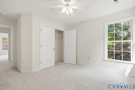 5213 Wheat Ridge Place, Chappell Ridge, Glen Allen, VA 23059 Bright room featuring neutral carpeting, a double-door closet with one door ajar, a ceiling fan with integrated lighting, and a multi-pane window overlooking greenery