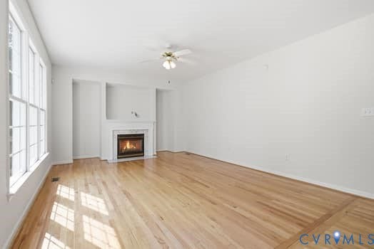 5213 Wheat Ridge Place, Chappell Ridge, Glen Allen, VA 23059 Hardwood flooring throughout, featuring a fireplace with a white mantel and surround, recessed wall alcoves, a multi-pane window, and a ceiling fan with integrated lighting