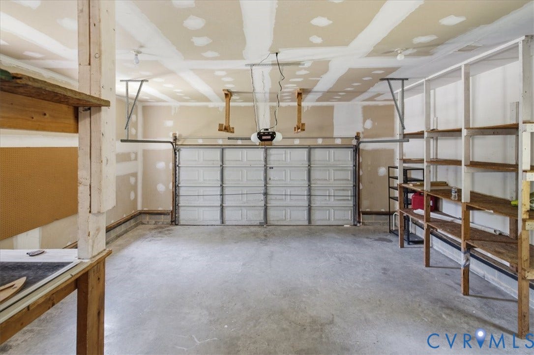 Spacious two-car garage - a sectional overhead door, automatic opener, concrete flooring, and extensive built-in shelving and workbenches