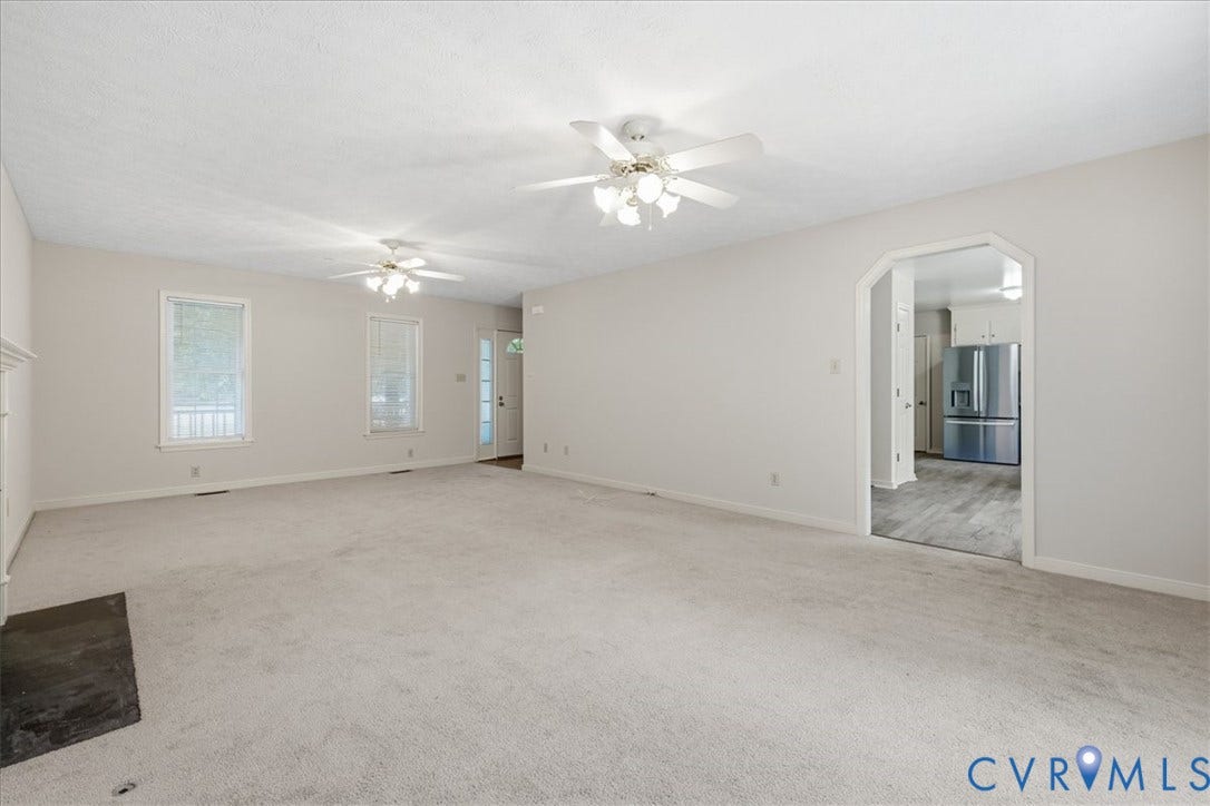 Spacious Family room featuring wall to wall  carpeting, two ceiling fans, and multiple windows